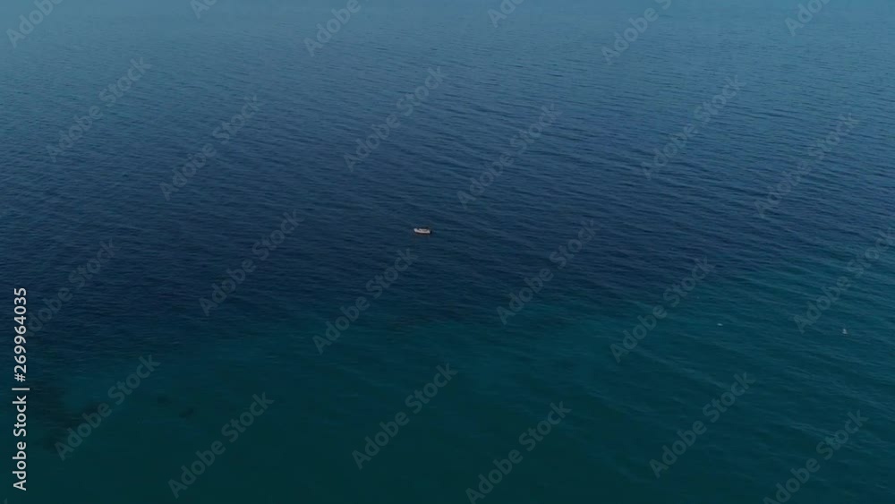 Small white fishing boat floating on the blue sea in the evening.Aerial//Greece//Halkidiki Small white fishing boat floating on the blue sea in the evening.Aerial//Greece//Halkidiki