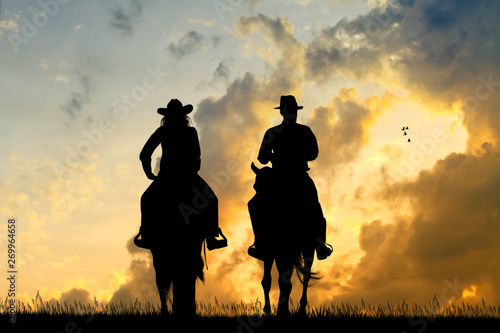 woman and man ride horses at sunset