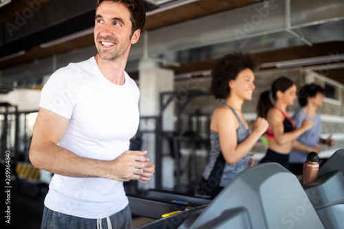 Happy fit people running on treadmill at fitness gym club