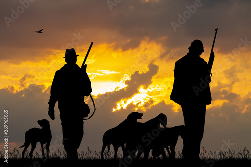 hunters with dogs at sunset