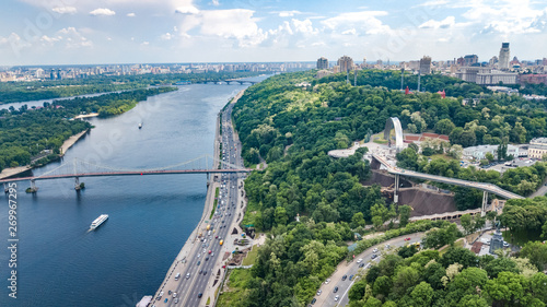 Aerial drone view of new pedestrian cycling park bridge construction, Dnieper river, hills, parks and Kyiv cityscape from above, city of Kiev skyline, Ukraine
