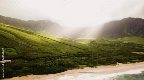 Short 4k drone shot capturing morning sun Flares coming over the mountains illuminating Makua Beach on the West Side of Oahu photo