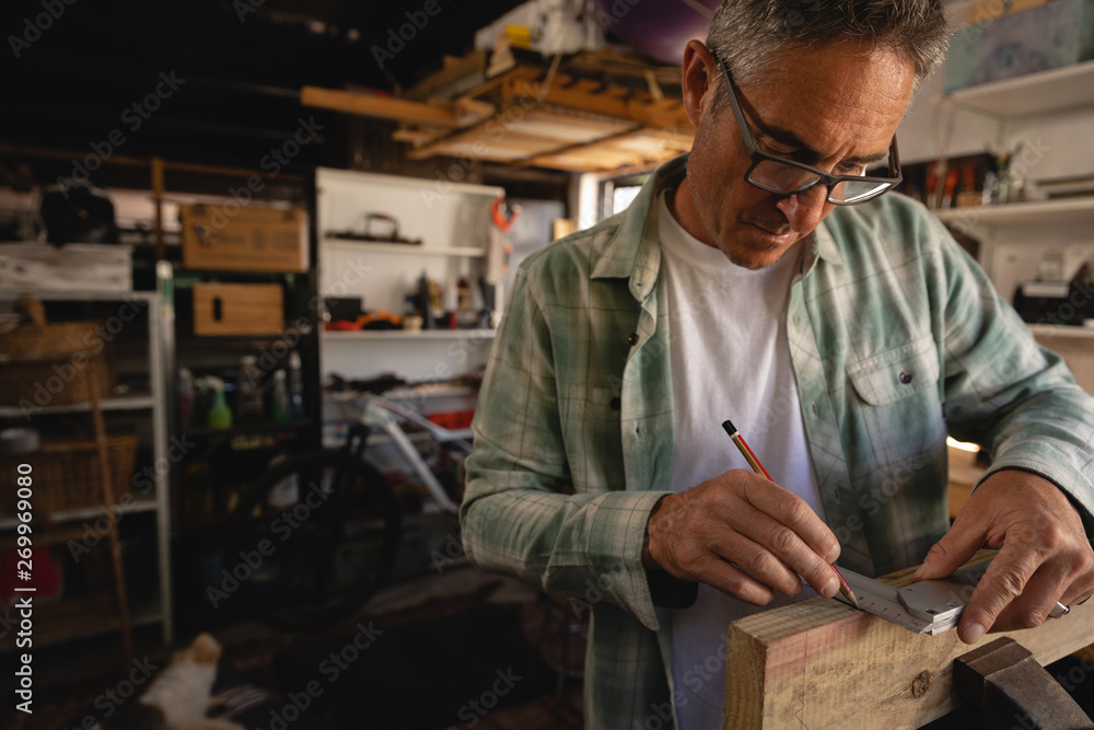 Carpenter using graduated square on wooden plank in workshop Carpenter using graduated square on wooden plank in workshop