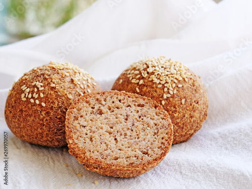 Tasty almond flour bread, homemade keto buns with crust and sesame seeds on white kitchen cloth