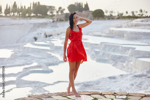 Girl in red dress on white travertines, Pamukkale
