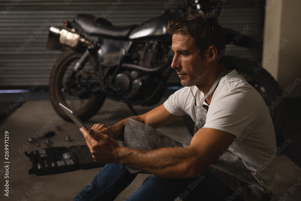 Bike mechanic using digital tablet in garage Bike mechanic using digital tablet in garage