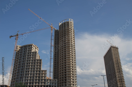 Big industrial tower crane with unfinished high raised building