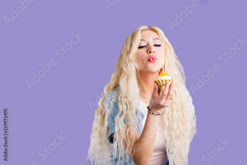 Happy lovely curly young woman holding birthday cupcake with candle