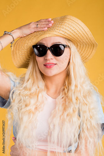 Close up photo of beautiful woman in sunglasses isolated on yellow background