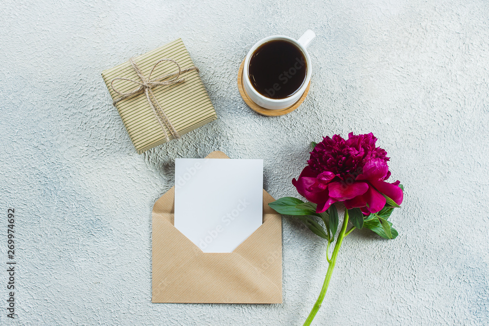 Morning coffee mug for breakfast, present box or gift, empty note, card and pink peony flowers on light stone table. Top view in flat lay style, copy space Morning coffee mug for breakfast, present box or gift, empty note, card and pink peony flowers on light stone table. Top view in flat lay style, copy space