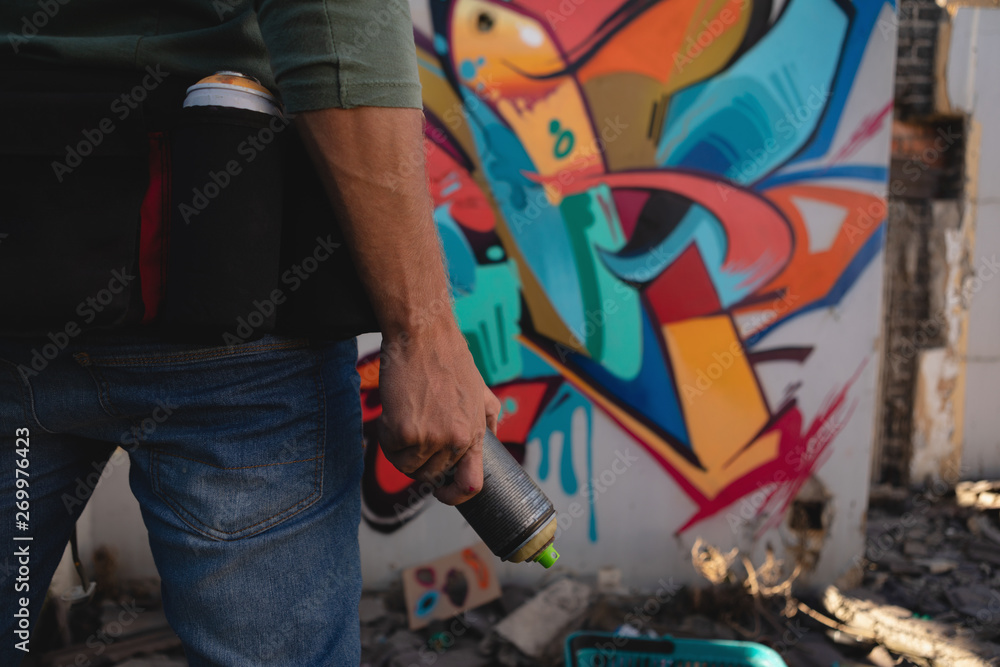 Graffiti artist standing with spray painting at alley Graffiti artist standing with spray painting at alley
