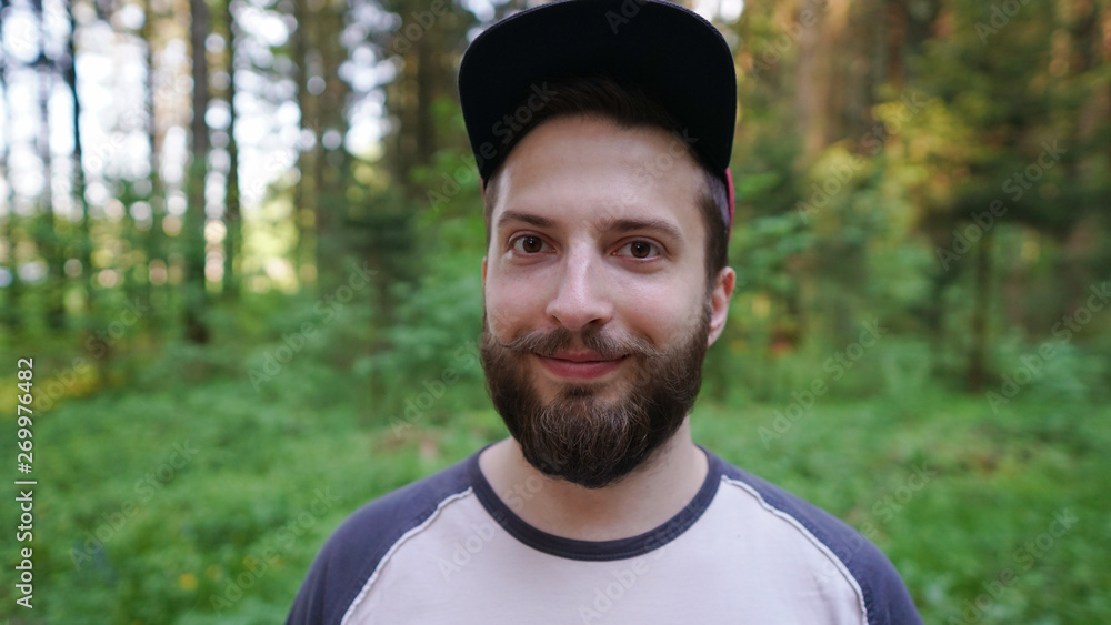 Portrait of smiling brutal bearded hipster man in the forest and he has a great chic mustache Portrait of smiling brutal bearded hipster man in the forest and he has a great chic mustache