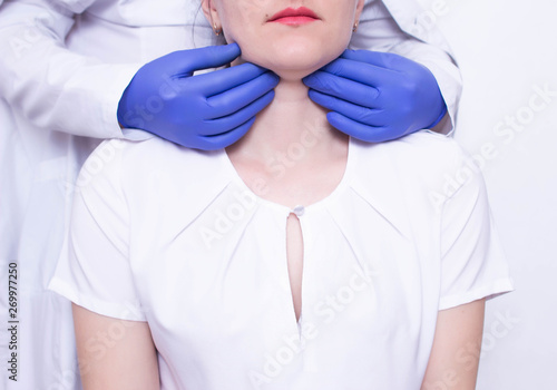Doctor specialist diagnoses palpation on the throat of the caucasian girl for the presence of enlarged lymph nodes and tumors, adenoids photo