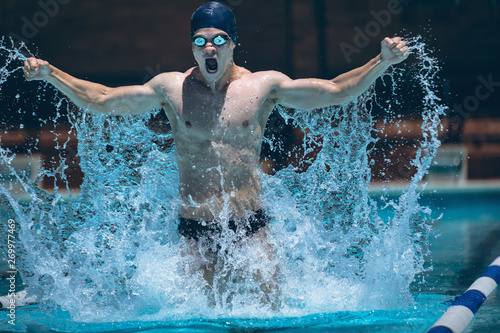 Young swimmer with arms stretched out celebrate victory in pool