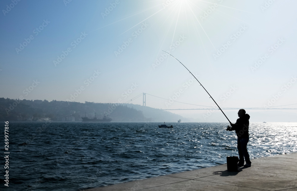 The man fishing in Istanbul in the bridge view.