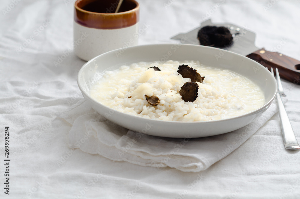 Risotto with black truffle and parmesan cheese on white linen tablecloth, Copyspace. Risotto with black truffle and parmesan cheese on white linen tablecloth, Copyspace.