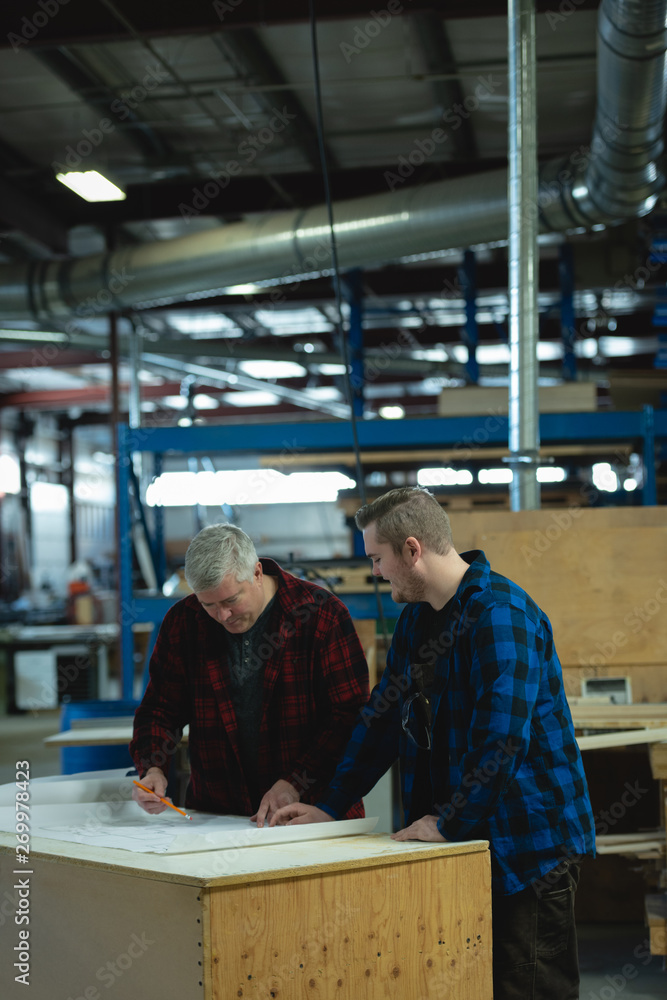Caucasians male carpenters discussing and measuring at workshop Caucasians male carpenters discussing and measuring at workshop