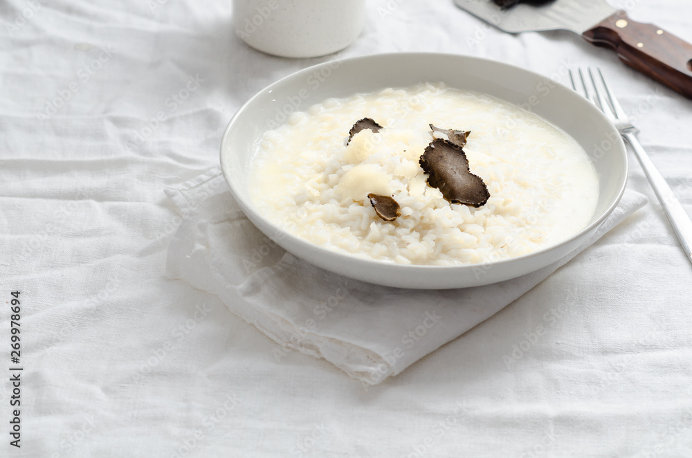Risotto with black truffle and parmesan cheese on white linen tablecloth, Copyspace. Risotto with black truffle and parmesan cheese on white linen tablecloth, Copyspace.