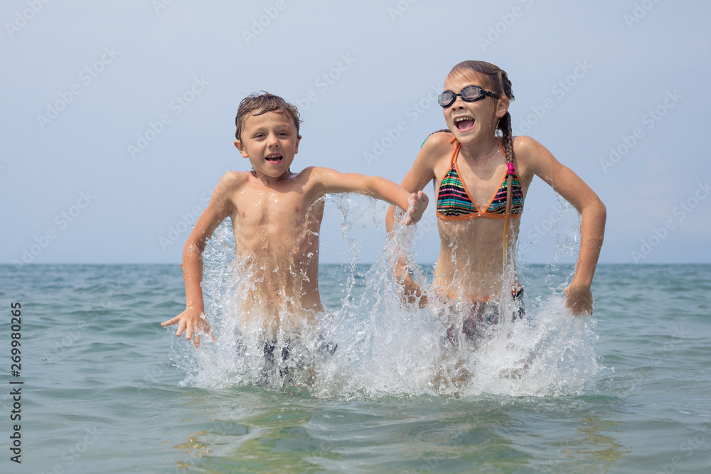 Two happy little children playing on the beach at the day time. Two happy little children playing on the beach at the day time.