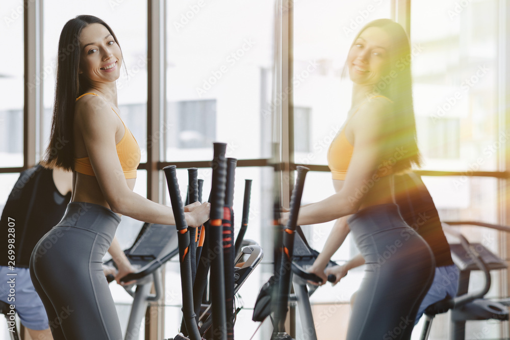 Fototapeta premium young attractive girl at gym on exercise bike, fitness and yoga