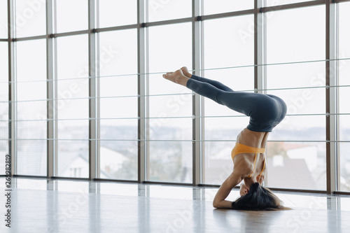 young attractive girl doing fitness exercises with yoga on the floor against the background of panoramic windows