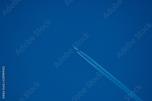 jet plane high in the blue sky with a contrail
