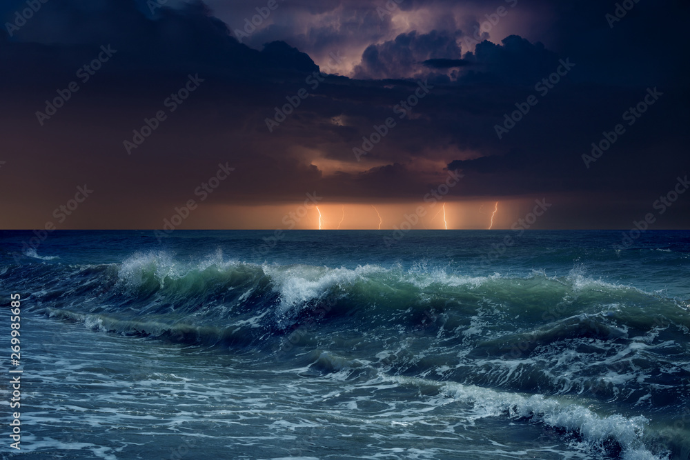 Huge lightnings in dark stormy sky above waving sea