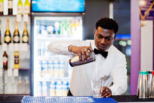 African american bartender at bar with shaker. Alcoholic beverage preparation.