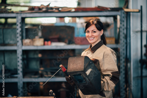 Portrait of a beautiful female welder at work, smiling at camera. photo
