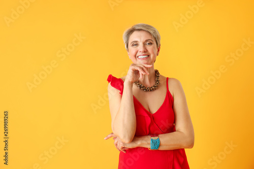 Fashionable mature woman on color background