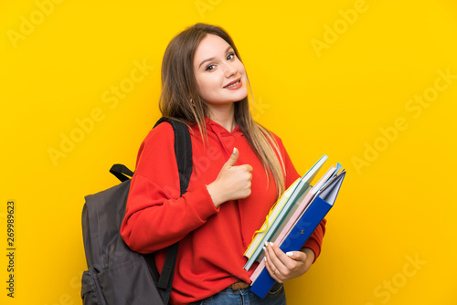 Teenager student girl over yellow background giving a thumbs up gesture