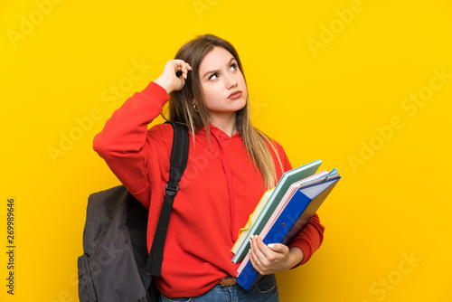 Teenager student girl over yellow background having doubts and with confuse face expression
