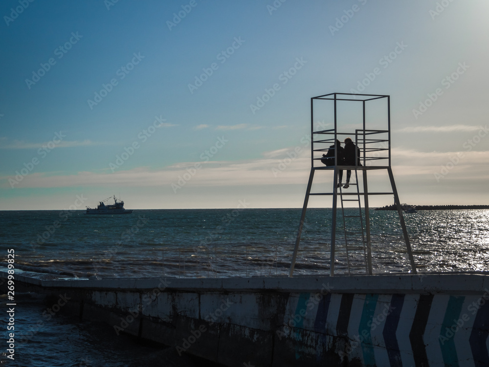 Silhouette of a loving couple on a lifeguard tower on the beach Silhouette of a loving couple on a lifeguard tower on the beach