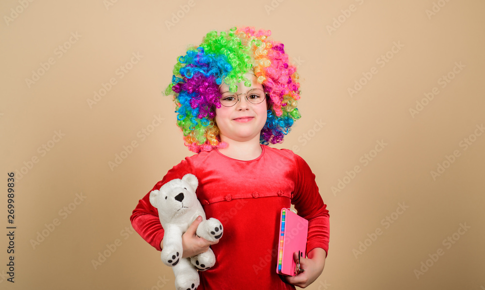Fototapeta premium Truly happy childhood. Girl cute playful child wear curly rainbow wig. Life is fun. Happy little child girl. International childrens day. Child care. Happy moments. Adorable baby having fun