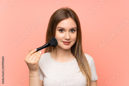 Teenager girl over pink background with makeup brush