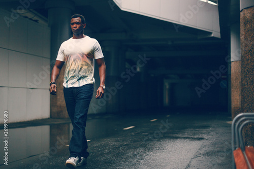 Black guy in a white T-shirt in a dark tunnel © photobyalex