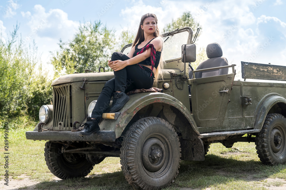 Fototapeta premium Portrait of beautiful long hair woman sitting on car hood