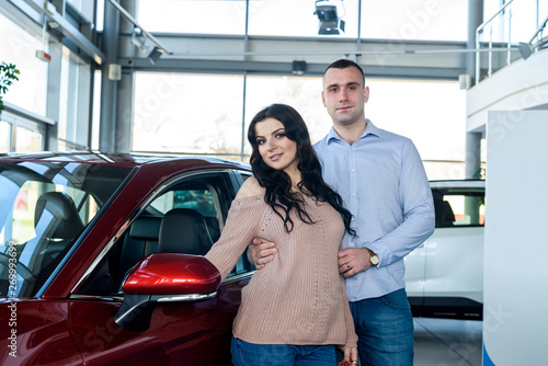 Happy family posing with car in showroom © RomanR