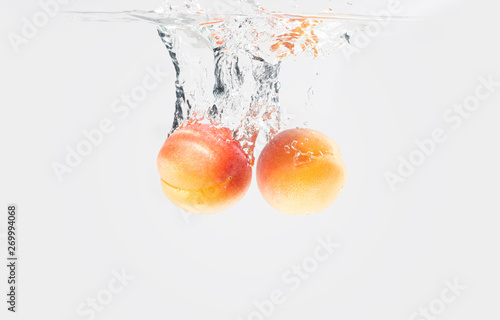 Two apricots dropped water with splash
