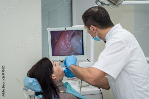 Dentist checking woman s teeth with mirror during visit