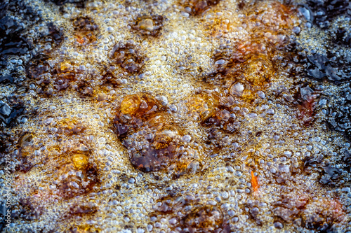 Boiling oil in frying pan for cooking. Thai street vendor sells grilled chicken legs meat at street food market in Thailand. Frying chicken legs in a pan close up