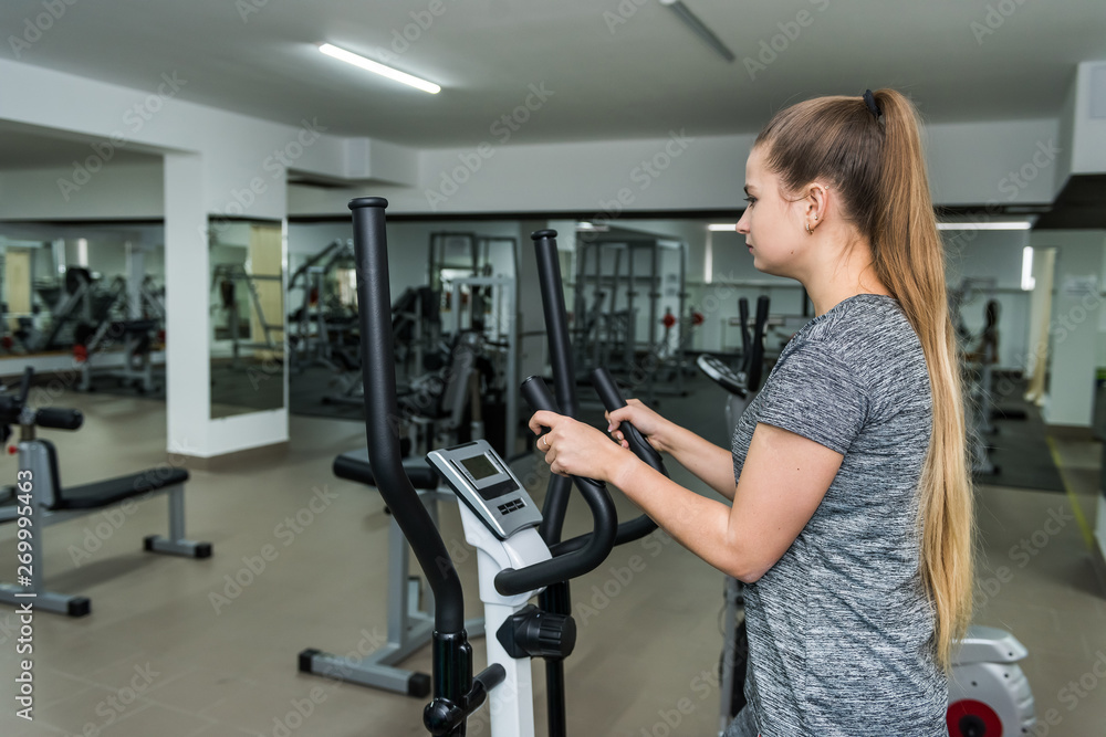 Fototapeta premium Cycling on exercise bikes. The girl is engaged in exercise bike in the gym