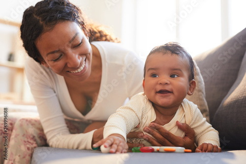 Positive loving young black mother spending beautiful time with her baby on maternity leave at home