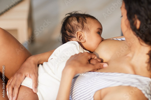 Fotografía Close-up of young black mother attaching baby at breast while giving nipple to s