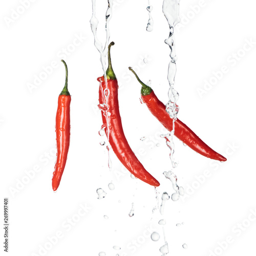 bright spicy red chili peppers with clear water streams isolated on white