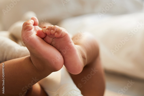 Fotografía Close-up of unrecognizable cute baby shaking feet while lying in bed, innocence