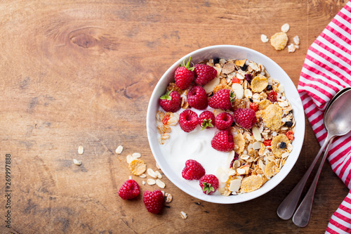 Healthy breakfast. Fresh granola, muesli with yogurt and berries on wooden background. Copy space. Top view.