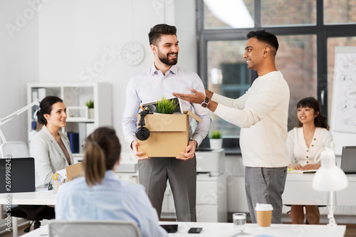business, new job and corporate concept - male employee with personal stuff meeting colleagues at office