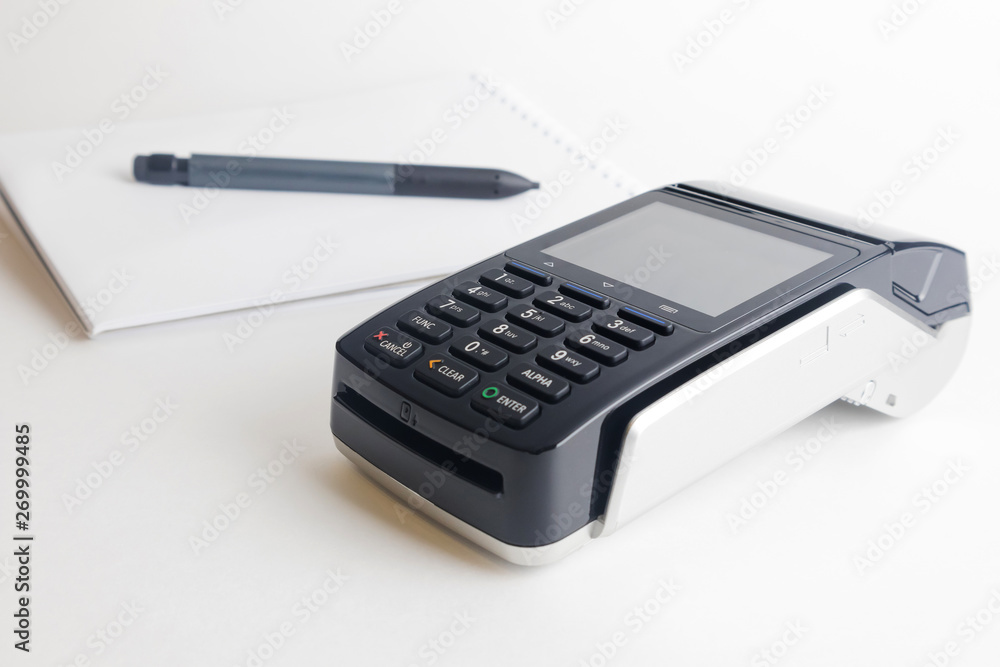 PPos terminal on a white background. In the background is a notebook and pen. Profos terminal on a white background. Banking equipment. Acquiring. Acceptance of bank credit cards. Contactless payment. PPos terminal on a white background. In the background is a notebook and pen. Profos terminal on a white background. Banking equipment. Acquiring. Acceptance of bank credit cards. Contactless payment.