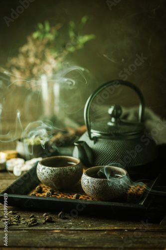 Still-life of japanese healthy green tea in a small cups and teapot over dark background